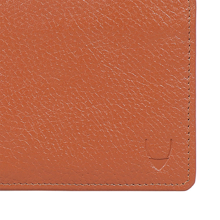 Close up view of men's tan leather bifold wallet texture with stitching & embossed logo details.