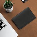 Black leather card holder wallet by Hidesign on desk beside laptop and plant, sleek everyday carry.