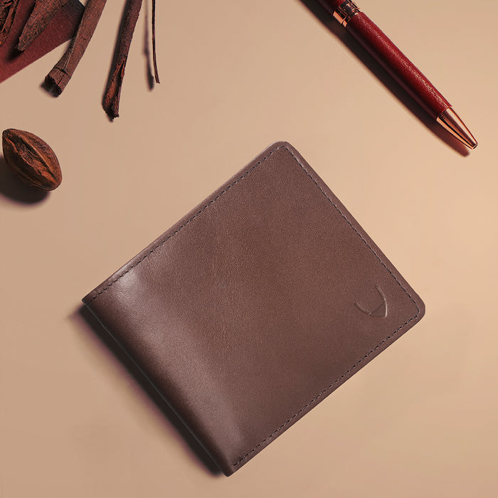 Tan leather bi-fold wallet styled with pen and accessories, featuring embossed Hidesign logo detail.