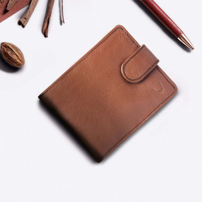 Brown leather Hidesign wallet placed on a white surface with spices & a pen for a stylish flat shot.
