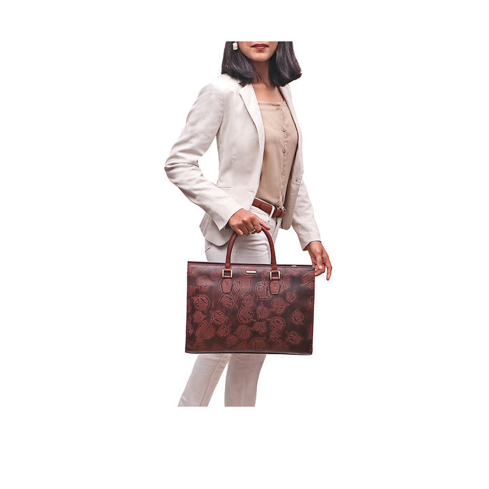 Woman in beige suit holding Kester brown leather laptop bag with leaf embossing & dual top handles.